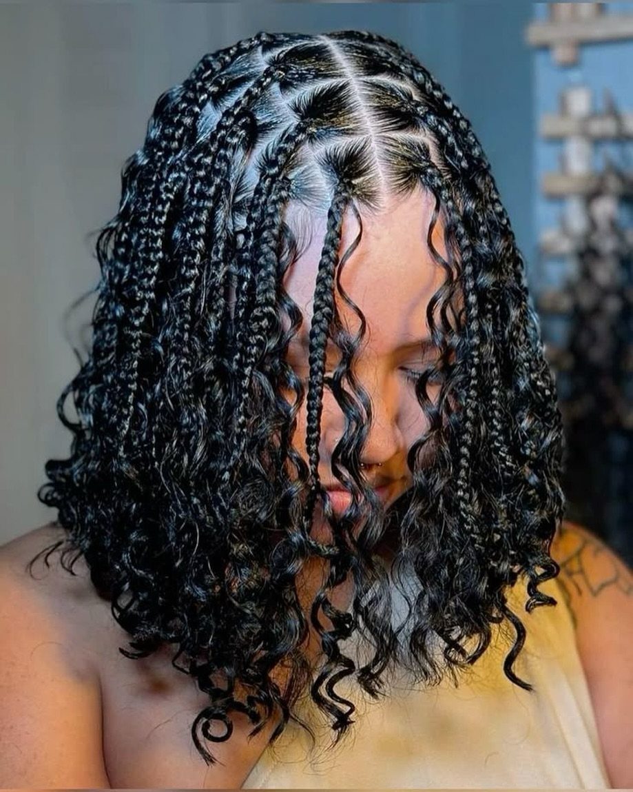 Shoulder-length curly hair with thin braids woven across the crown