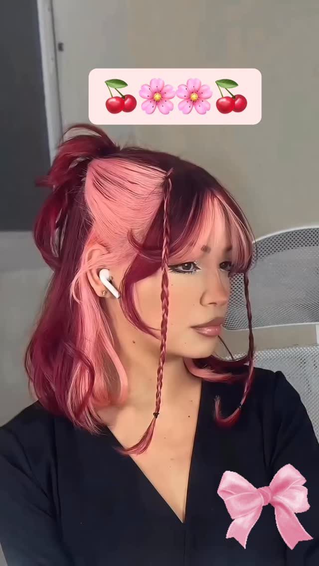 Short pink hair styled with thin face-framing braids and a tied crown section