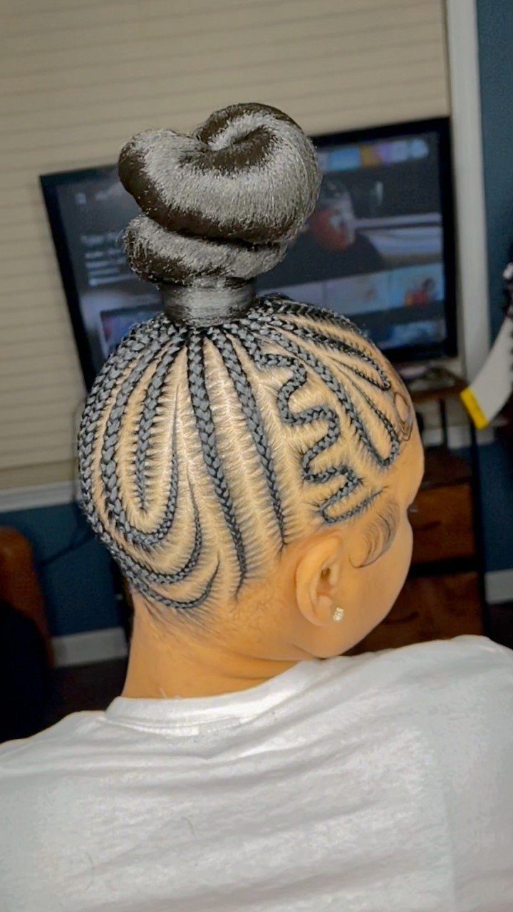 Cornrow braids gathered into a bun on a short-haired person's head