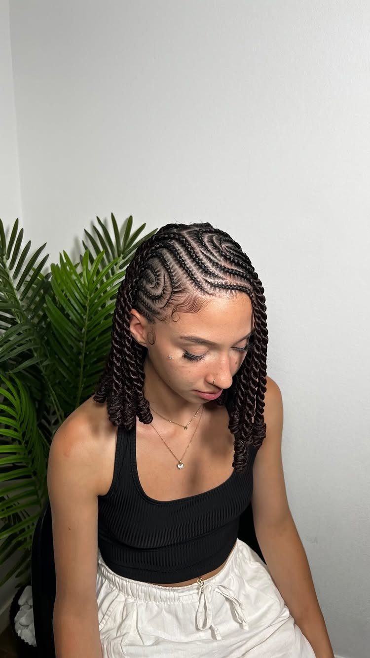 Short cornrow braids and twists styled on a woman seated beside a plant