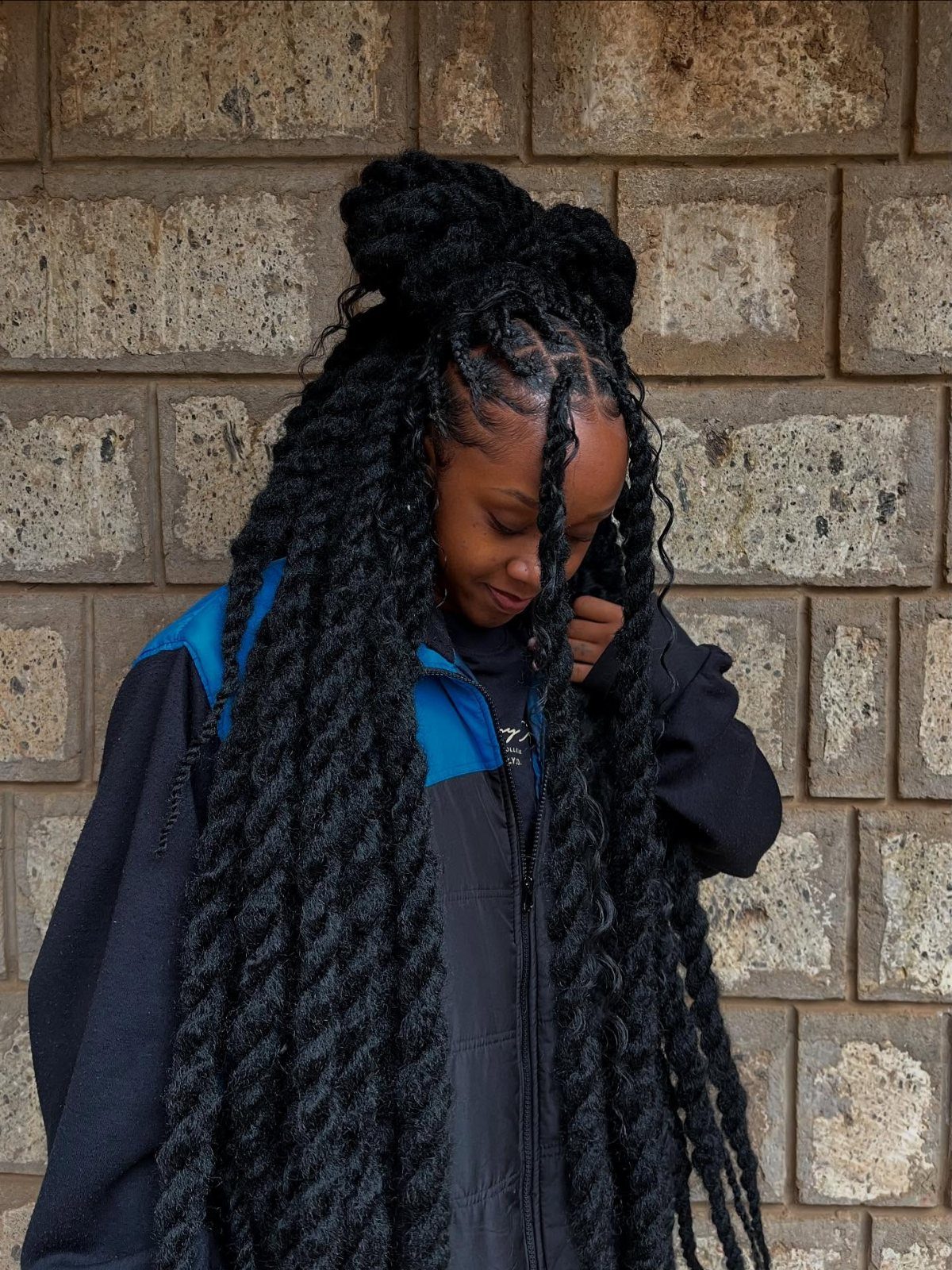 Long black twists fall past a woman’s waist, with some hair gathered into a high bun.