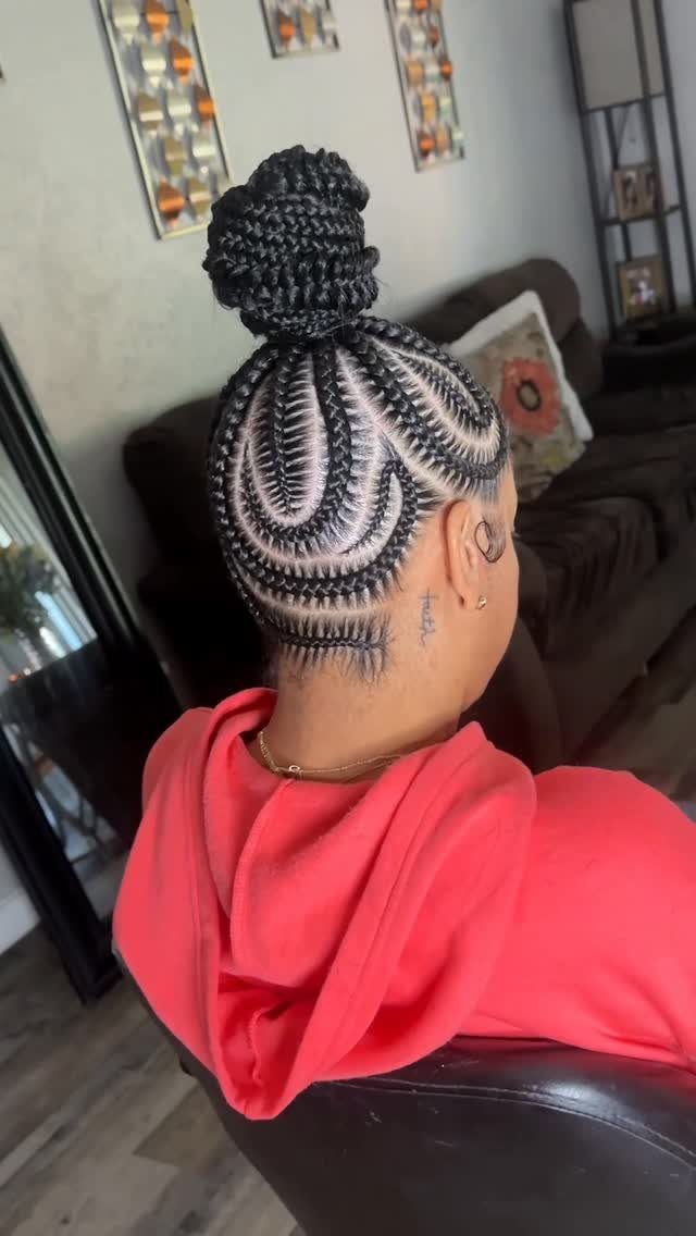 Braided top bun above curved cornrows on a seated person