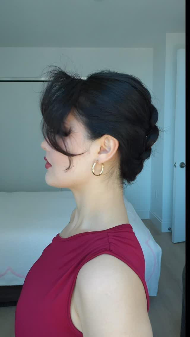 Woman in profile showing a braided low bun with swept dark hair