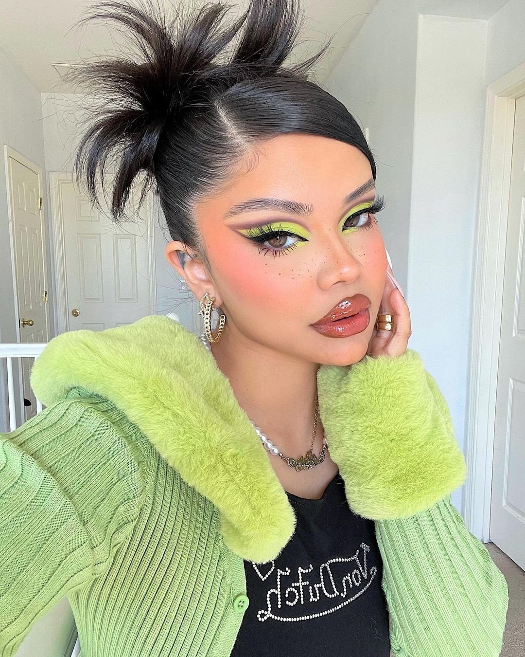 High bun with loose hair ends sticking up on a person posing indoors