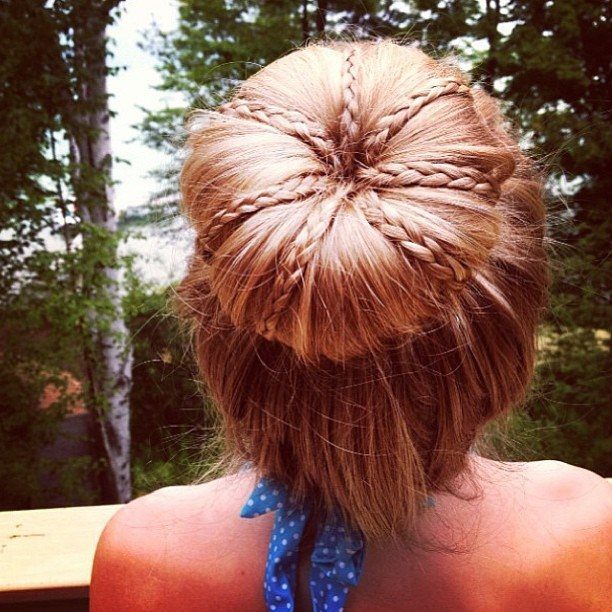 Auburn hair bun with slim braids crossing over it, viewed from behind