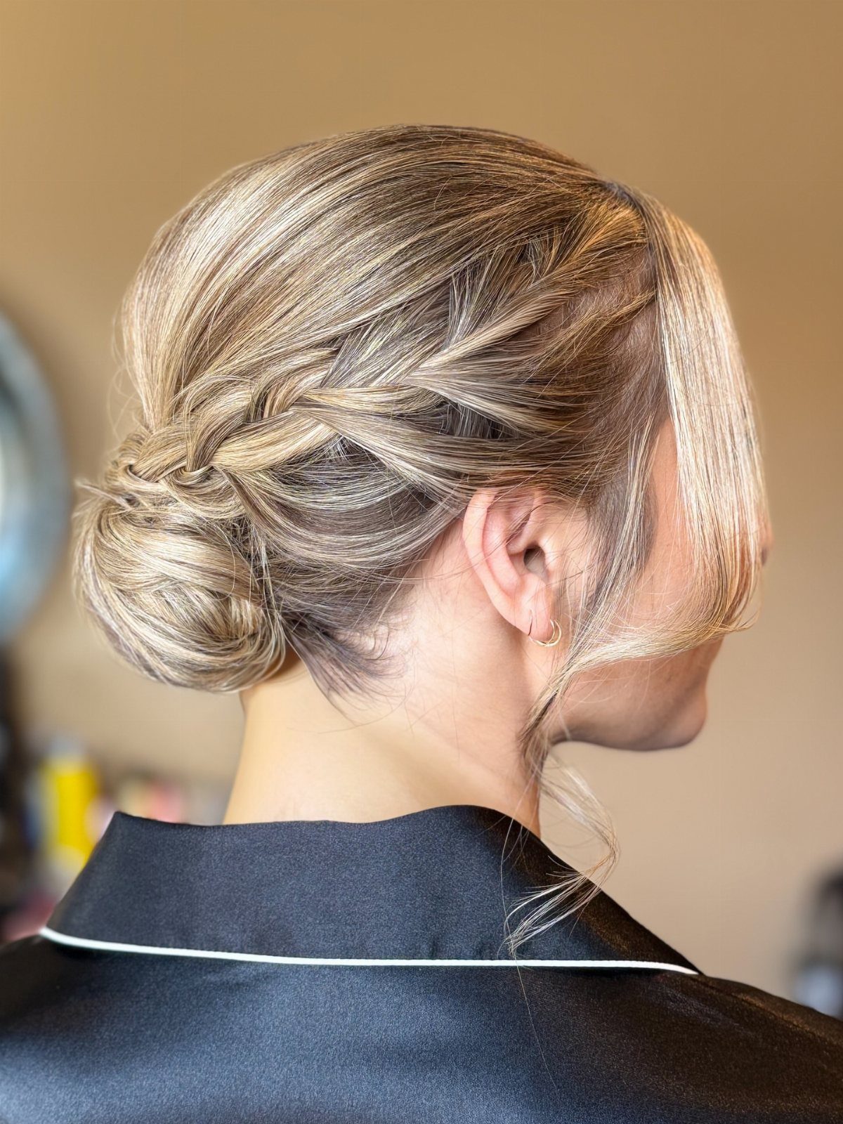 Braided blonde bun gathered at the nape, with loose face-framing strands