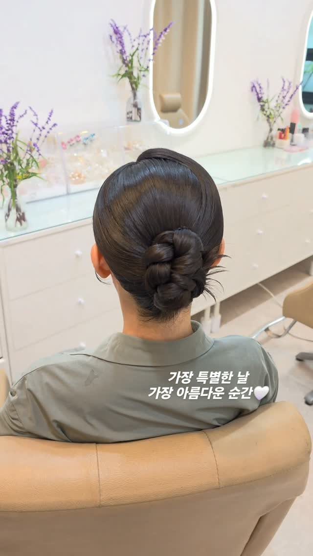 Low braided bun viewed from behind in a salon chair