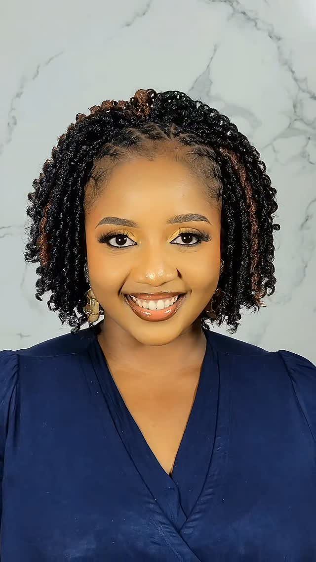 Woman with short, fine crochet braids poses against a pale wall