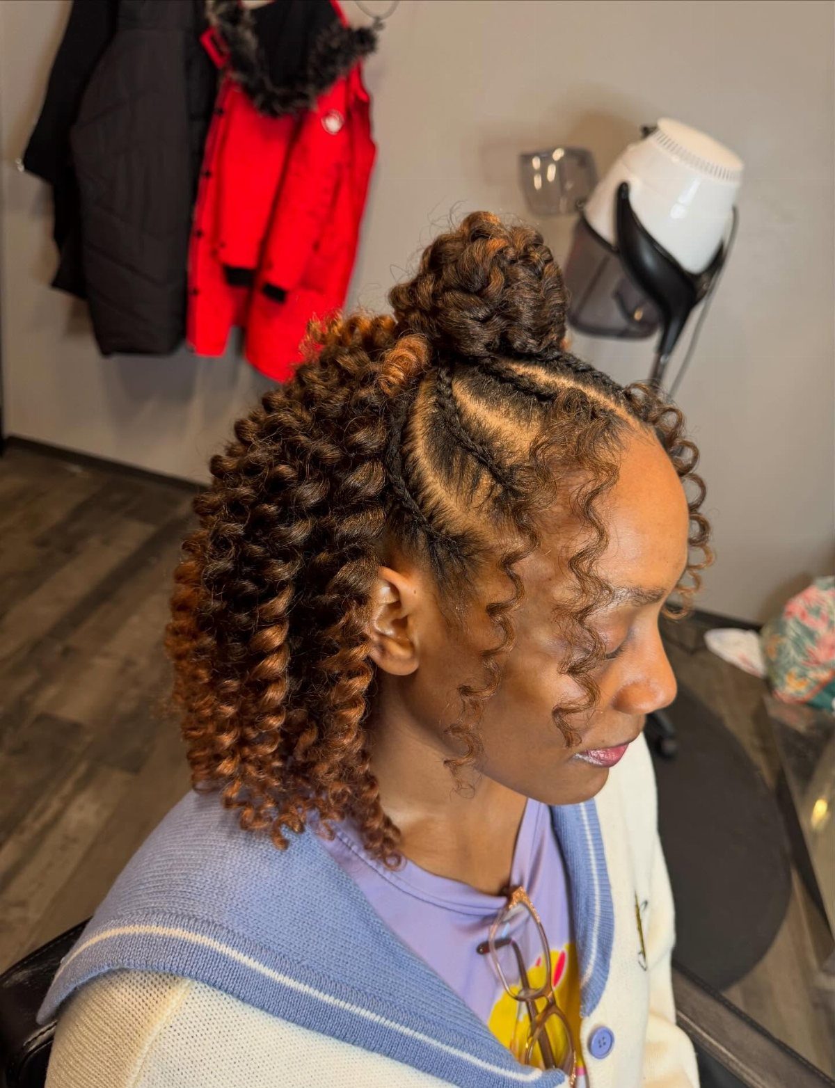 Woman with top cornrows meeting loose brown curls in a half-cornrow half-crochet style