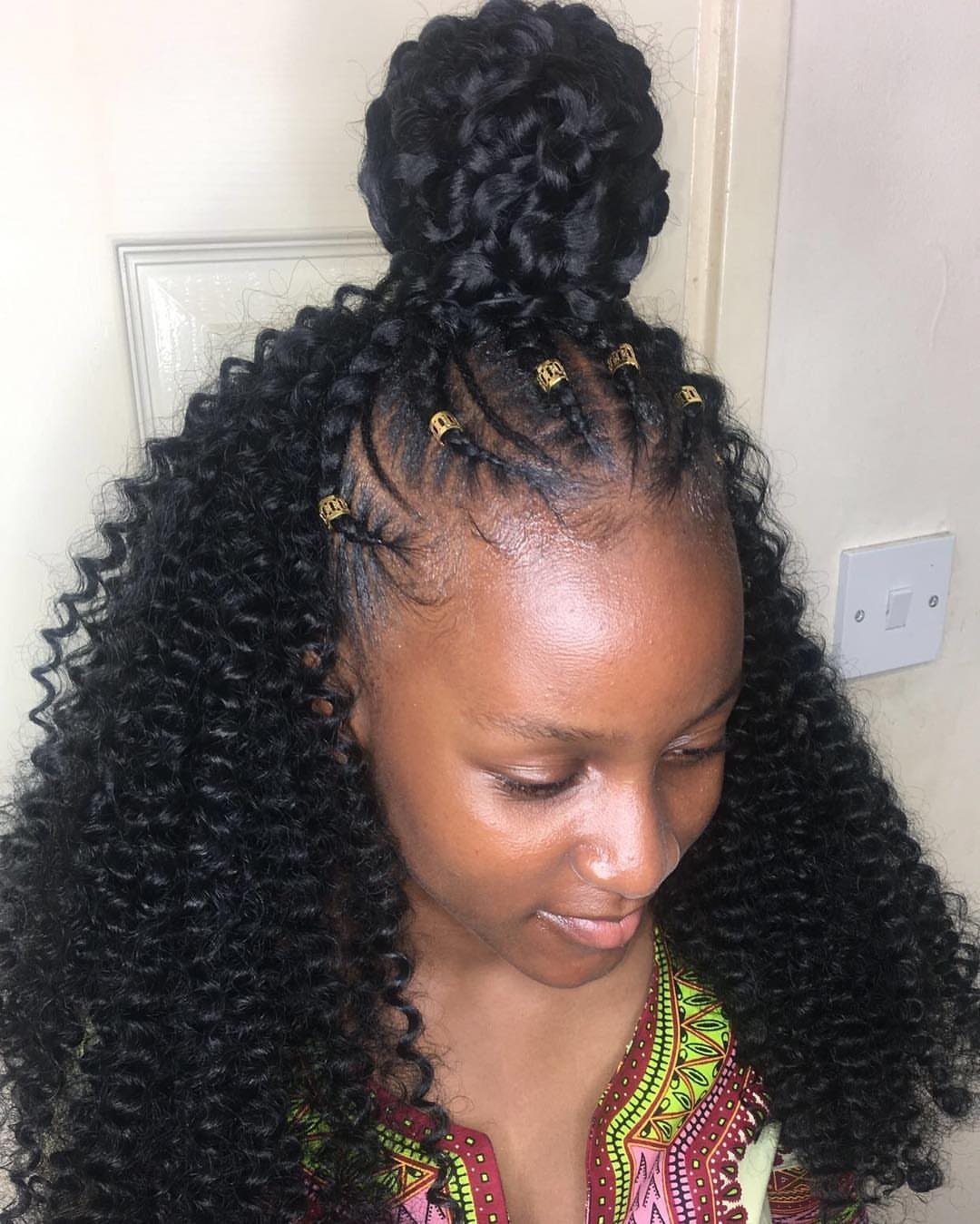 Woman with curly crochet braids gathered into a high half-up top knot