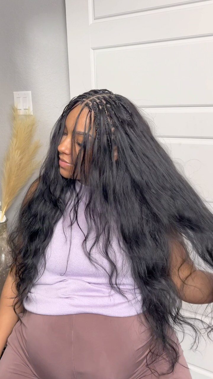 Woman wearing long dark crochet-style hair with loose curls and fine front braids