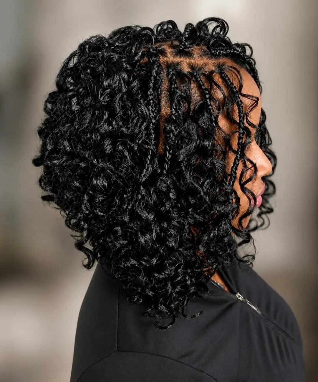 Side-profile person showing voluminous curly bohemian crochet braids with loose ringlets