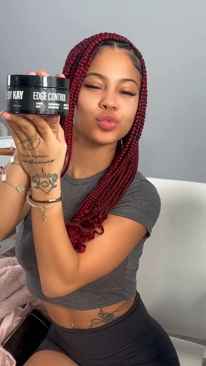 Woman posing with long burgundy braids falling over one shoulder