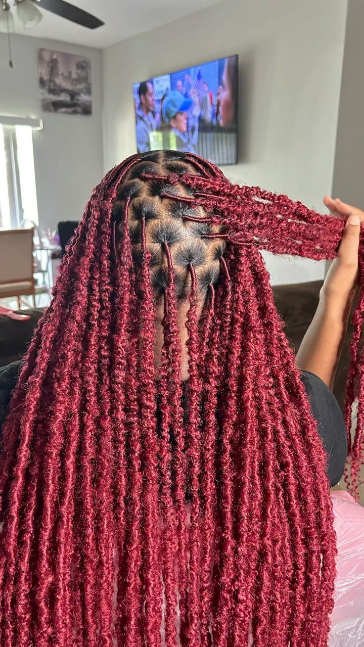 Burgundy butterfly locs held aside to show their looped texture and scalp parting