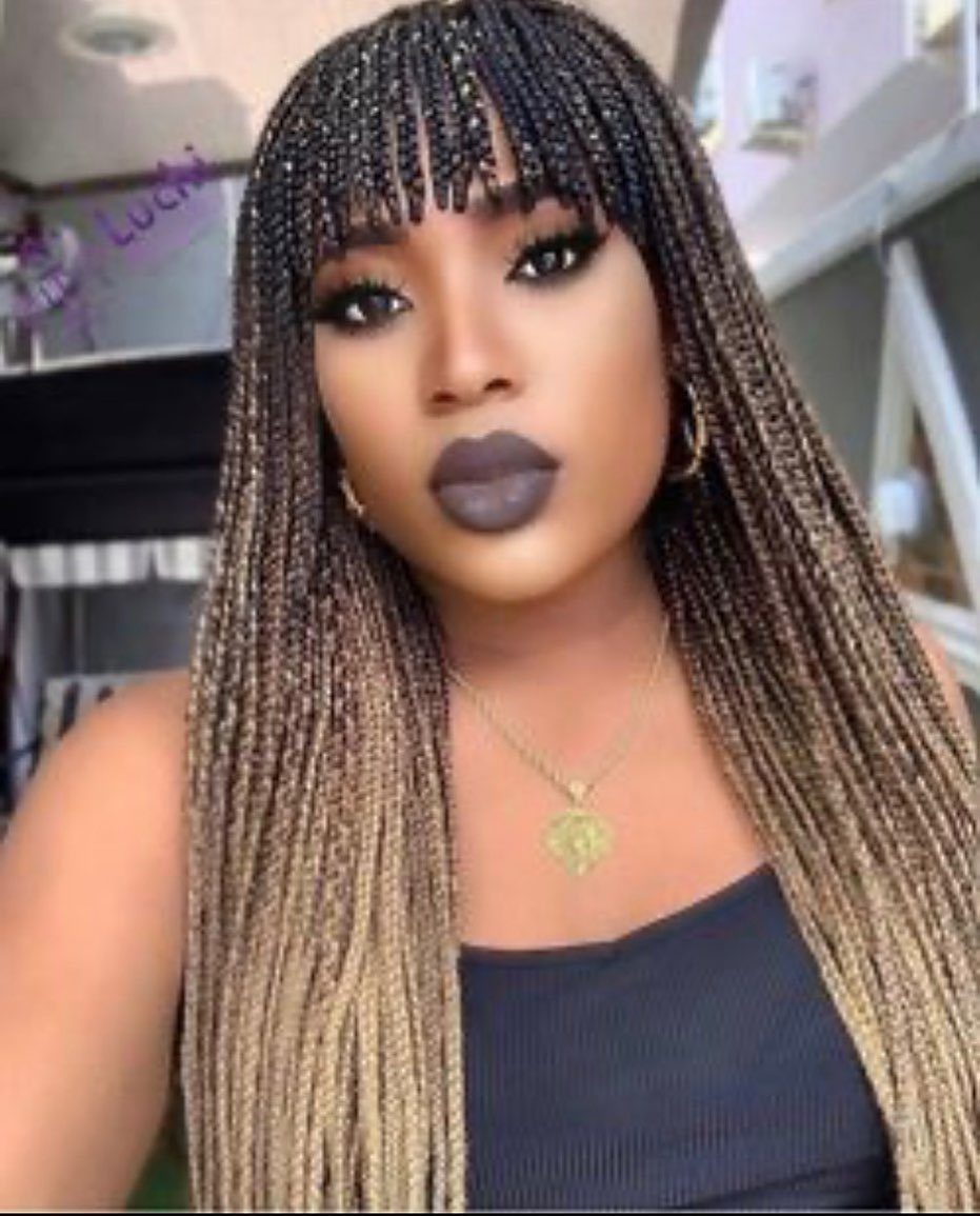 Woman posing with long crochet braids and a straight fringe across her forehead