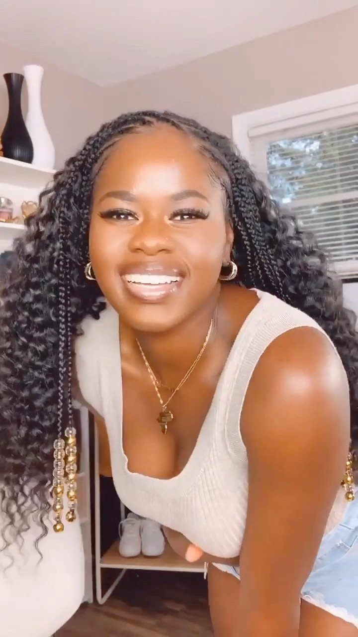 Woman with long black crochet braids adorned with gold beads
