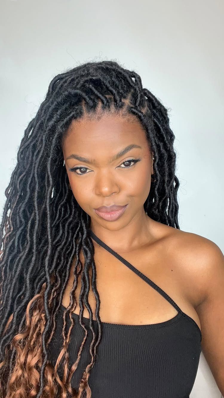 Woman wearing long dark crochet faux locs with brown ends and a black one-shoulder top
