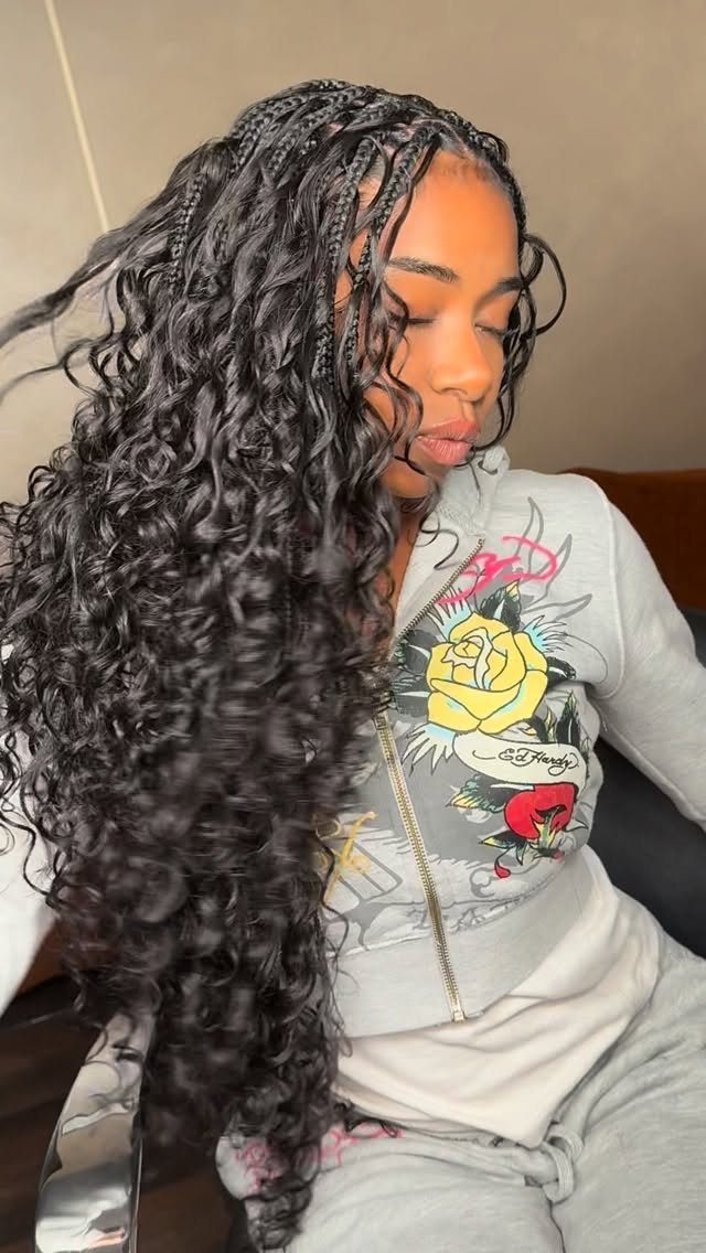 Woman displaying long layered crochet braids with loose black curls and braided roots