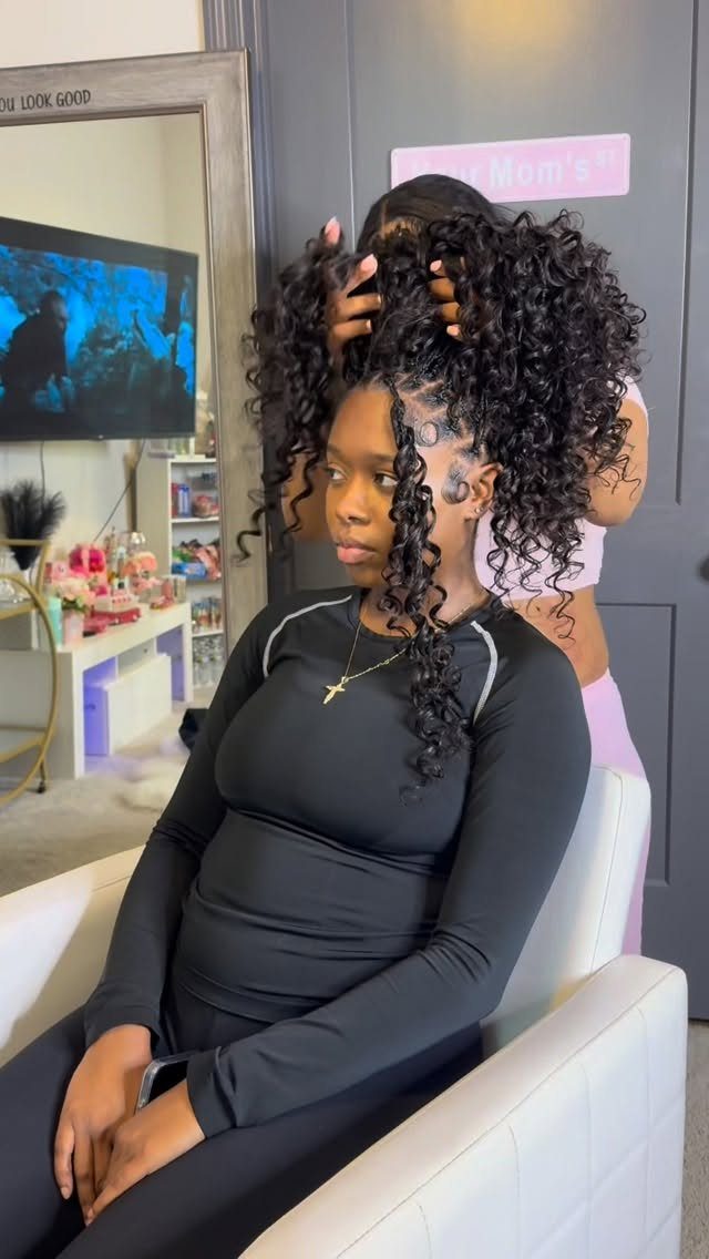 Woman showing a black curly crochet braid updo with long face-framing tendrils