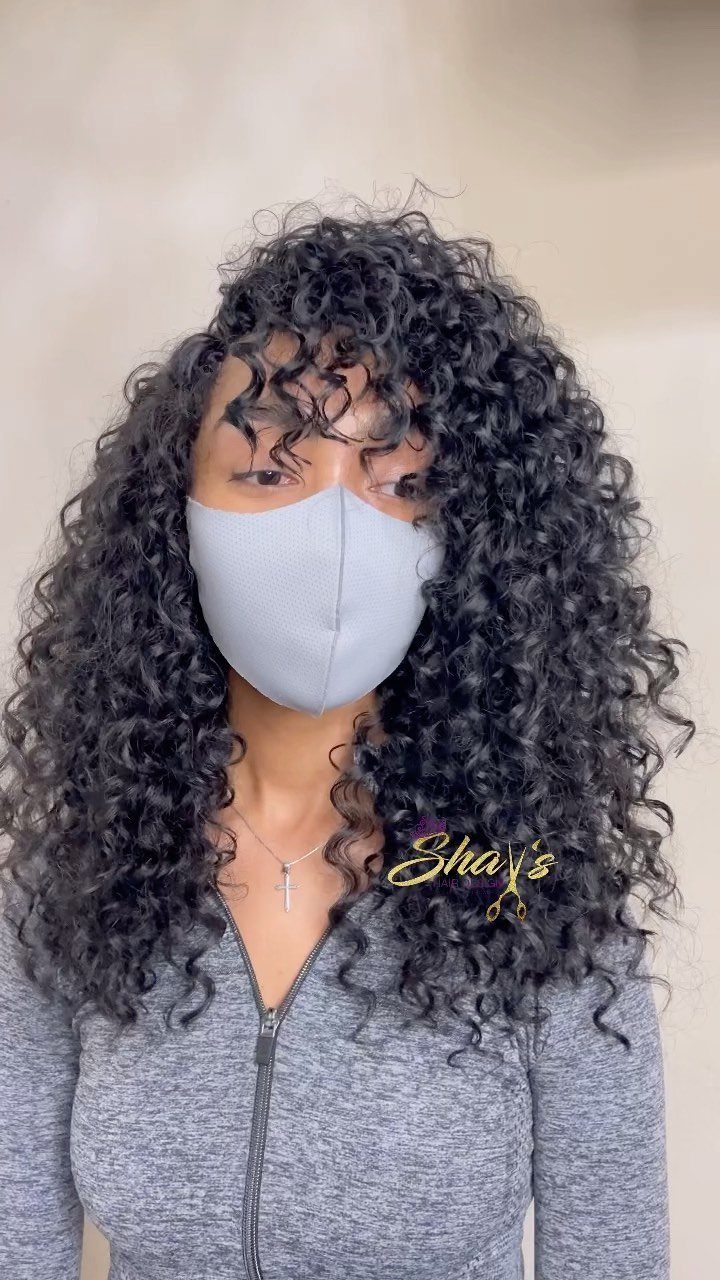 Person wearing long, voluminous black curly crochet braids with a gray mask