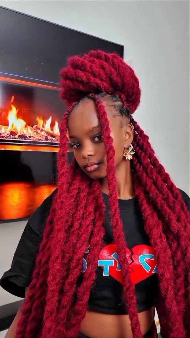 Woman wearing long, thick burgundy crochet box braids with a high bun