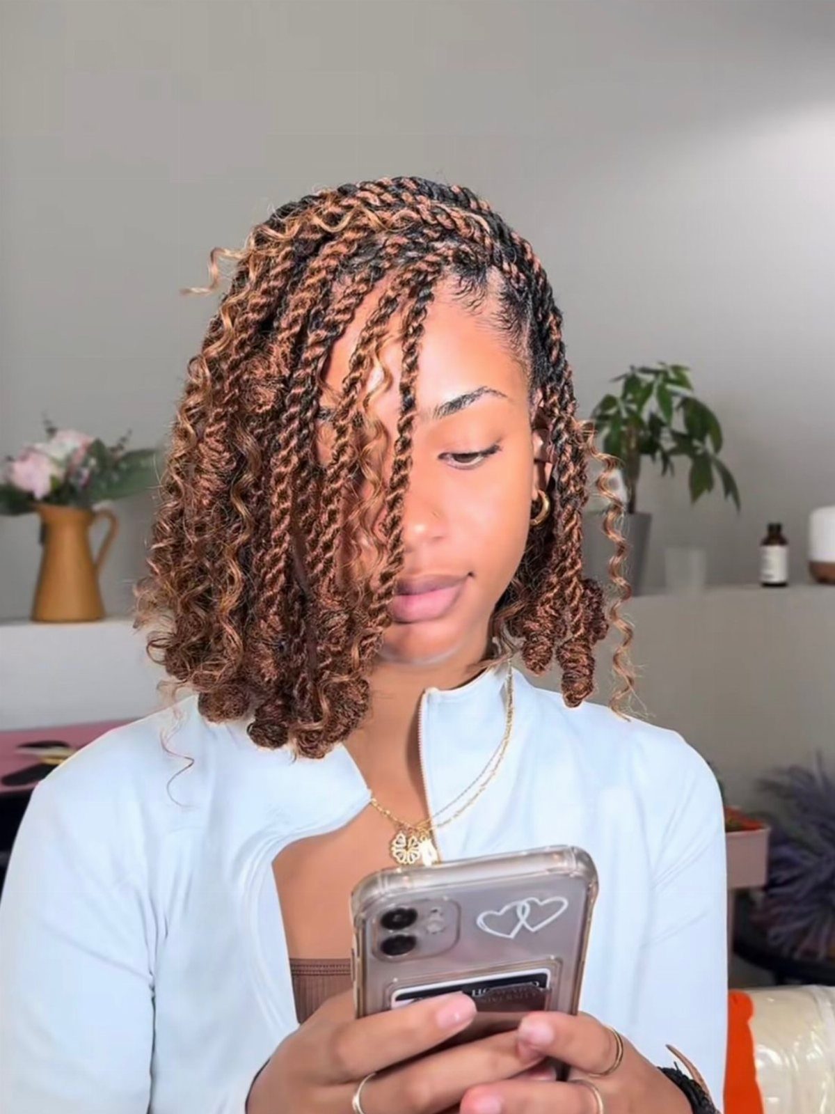 Woman showing shoulder-length curly crochet braids with copper highlights in a mirror selfie