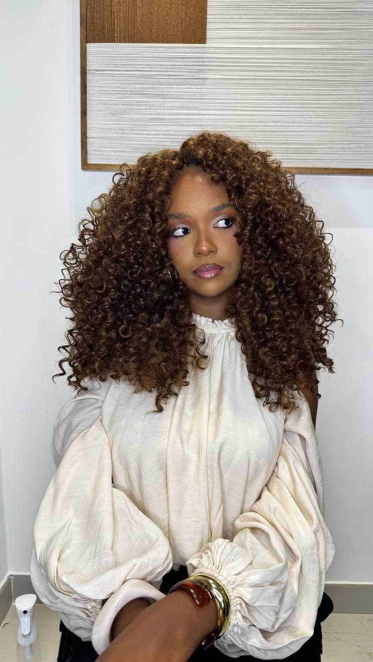 Woman with voluminous dark ringlets in layered lengths wearing a white blouse
