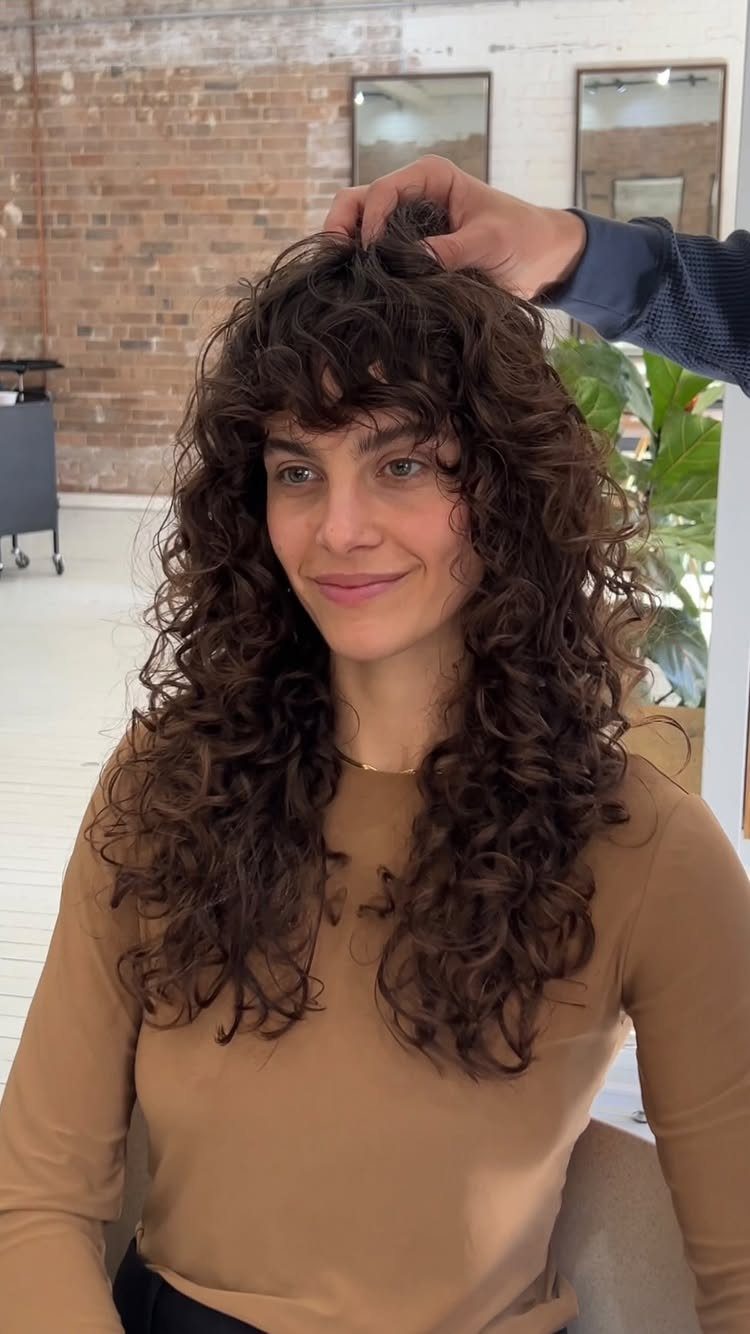 Woman with long curly shag layers and bangs in a salon
