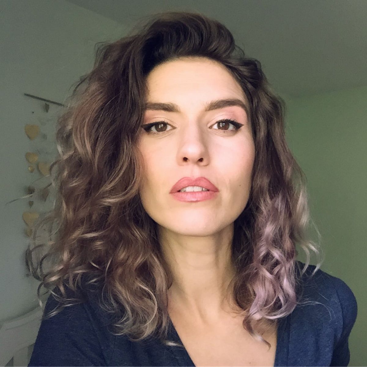 Woman displaying shoulder-length brown curls with subtle layers and lighter highlights