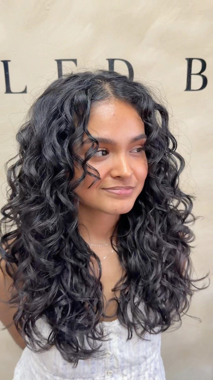 Woman showing long dark curls with layers in a balanced rounded silhouette