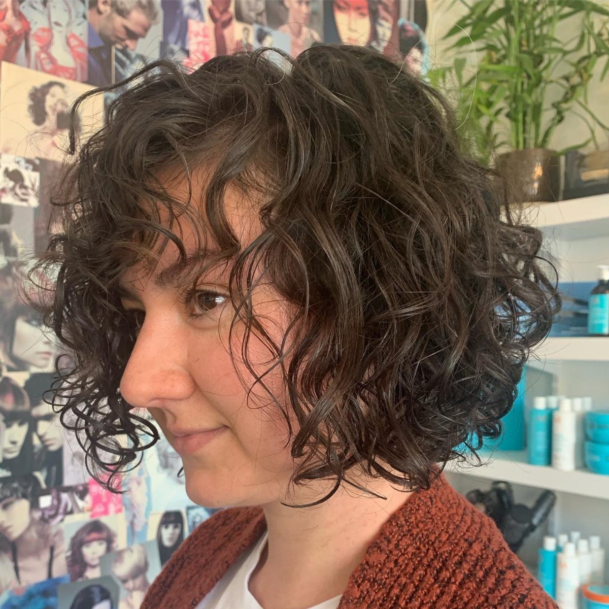 Woman with dark curly shaggy bob and face-framing bangs in a salon