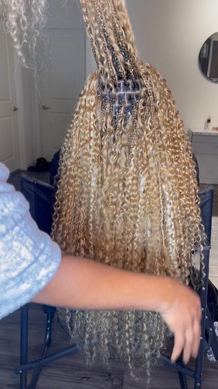 Blonde box braids with long, voluminous curled ends being styled