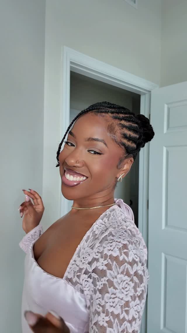 Smiling woman displays cornrows gathered into a bun at the back