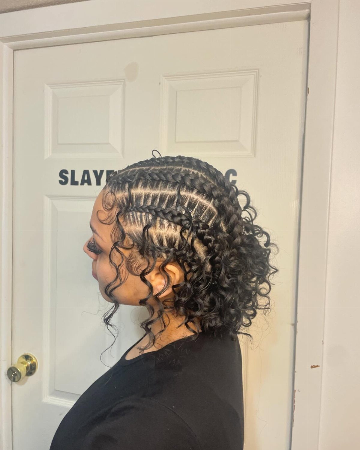 Crossing cornrows meet loose black curls around the sides and back