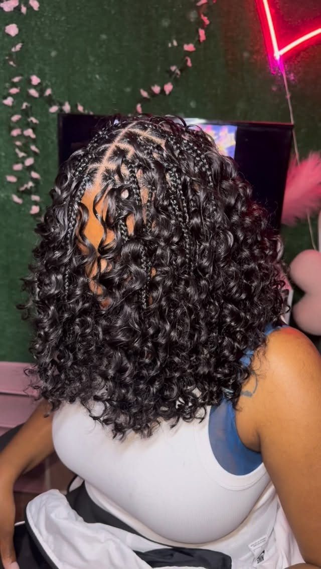Shoulder-length dark braids and curls cover the back of a seated person’s head