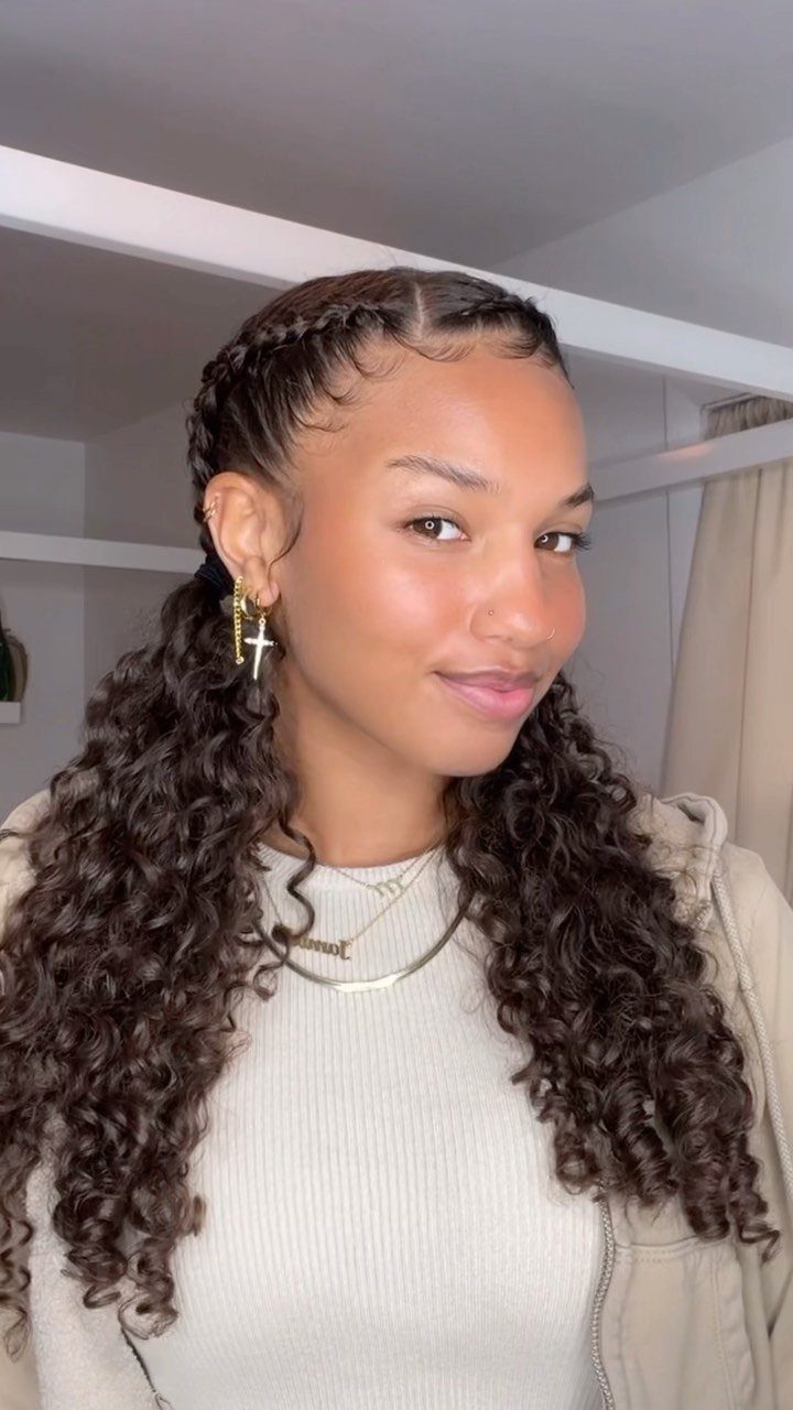 Woman wearing center-parted braids that blend into long, loose dark curls