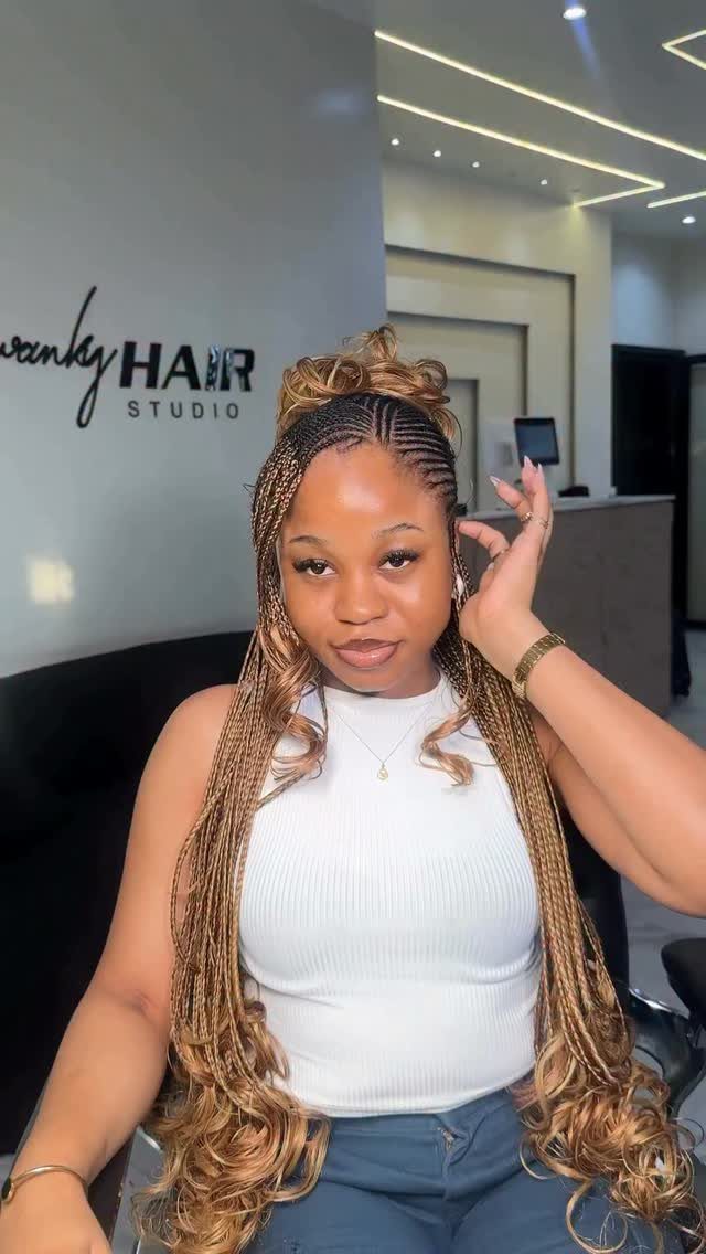 Woman displays long brown braids with curled ends in a salon