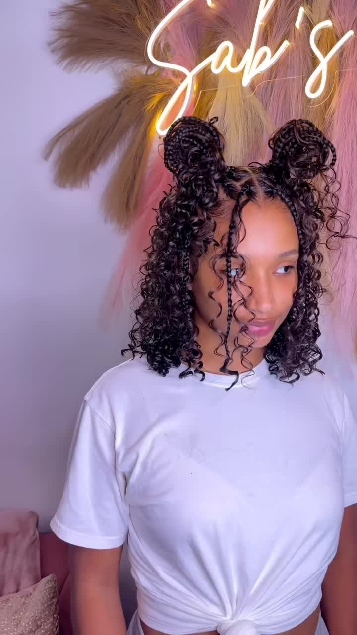 Woman wearing two braided space buns with loose black curls around her face