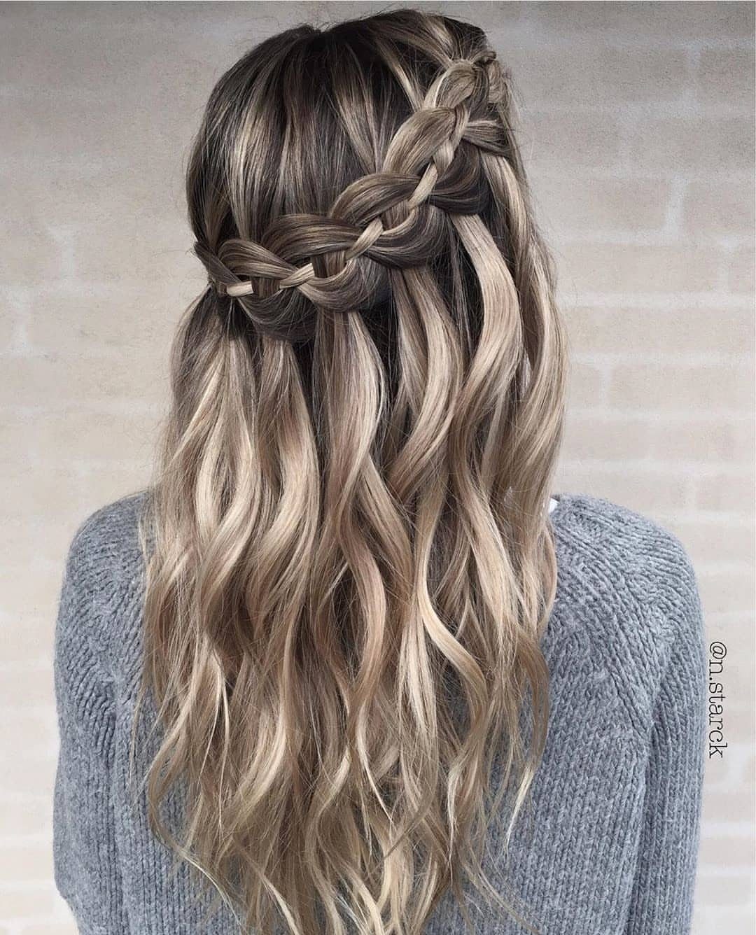Waterfall braid crosses the back of long, loose blonde waves