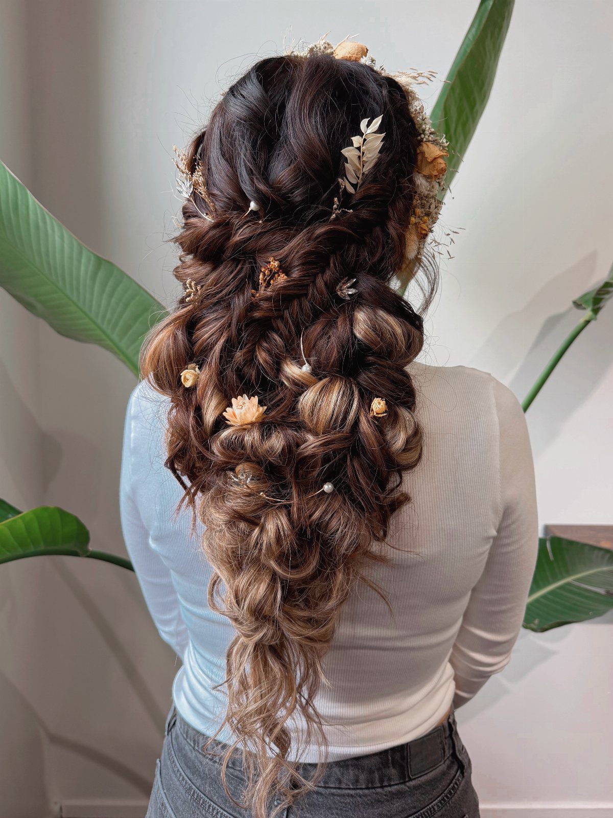Long loose bridal braid decorated with small flowers and a gold leaf hairpin