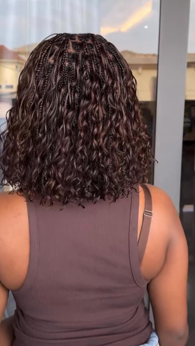 Shoulder-length dark curls with small braids along the crown