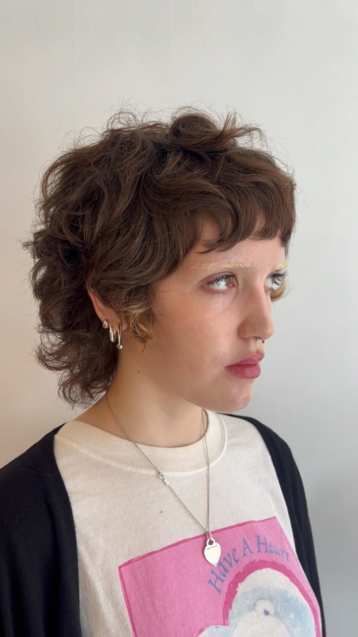 Short brown curly pixie cut with tousled layers framing the face