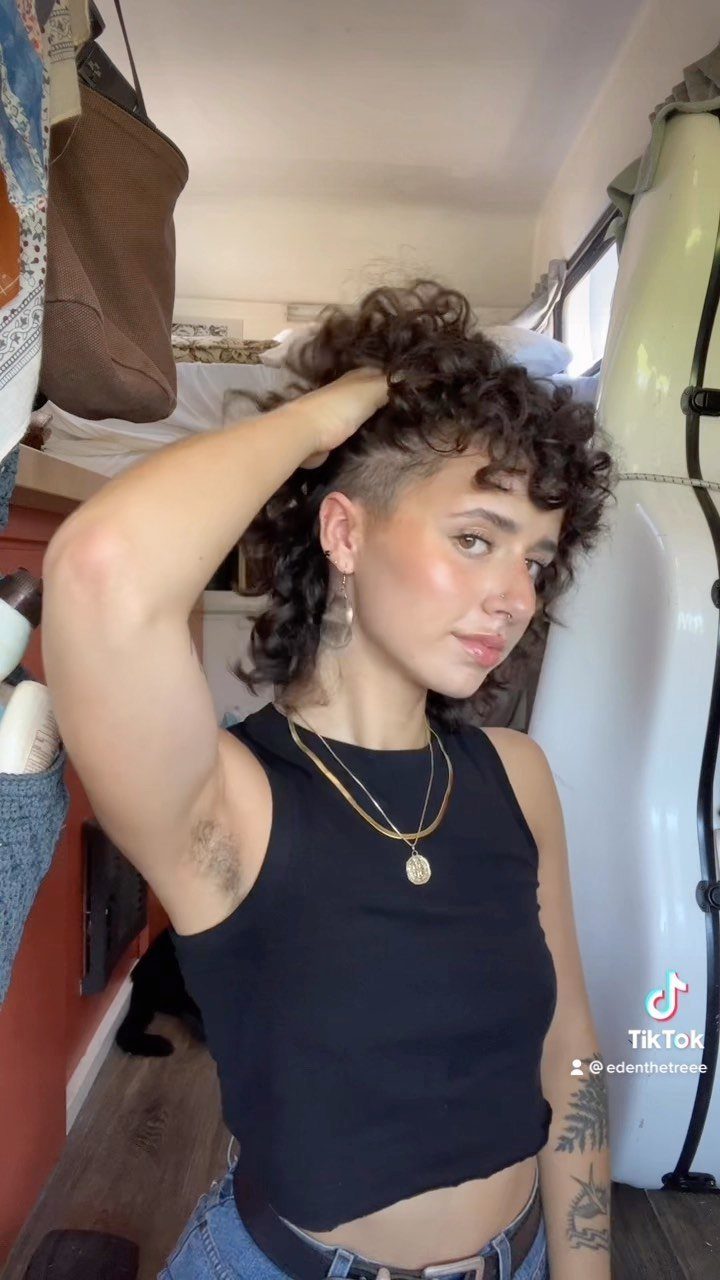 Person lifts curly pompadour hair, revealing the closely trimmed sides