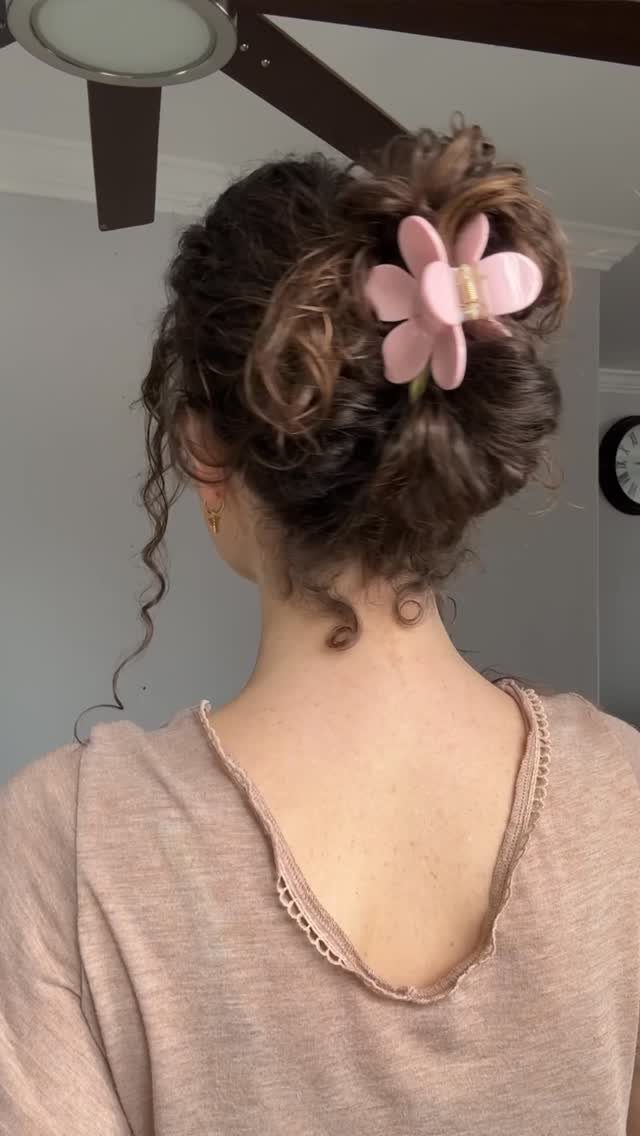 High curly updo decorated with a large pink flower clip