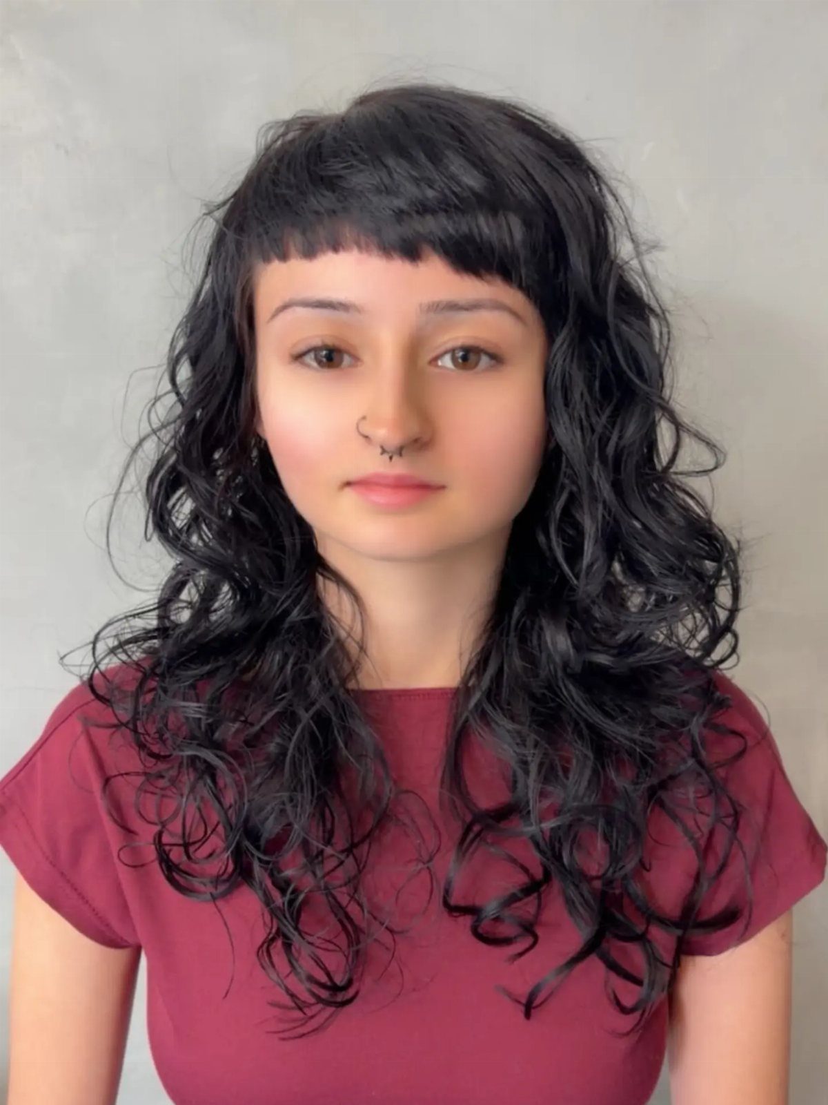 Person with long black curls and a blunt, straight-across fringe