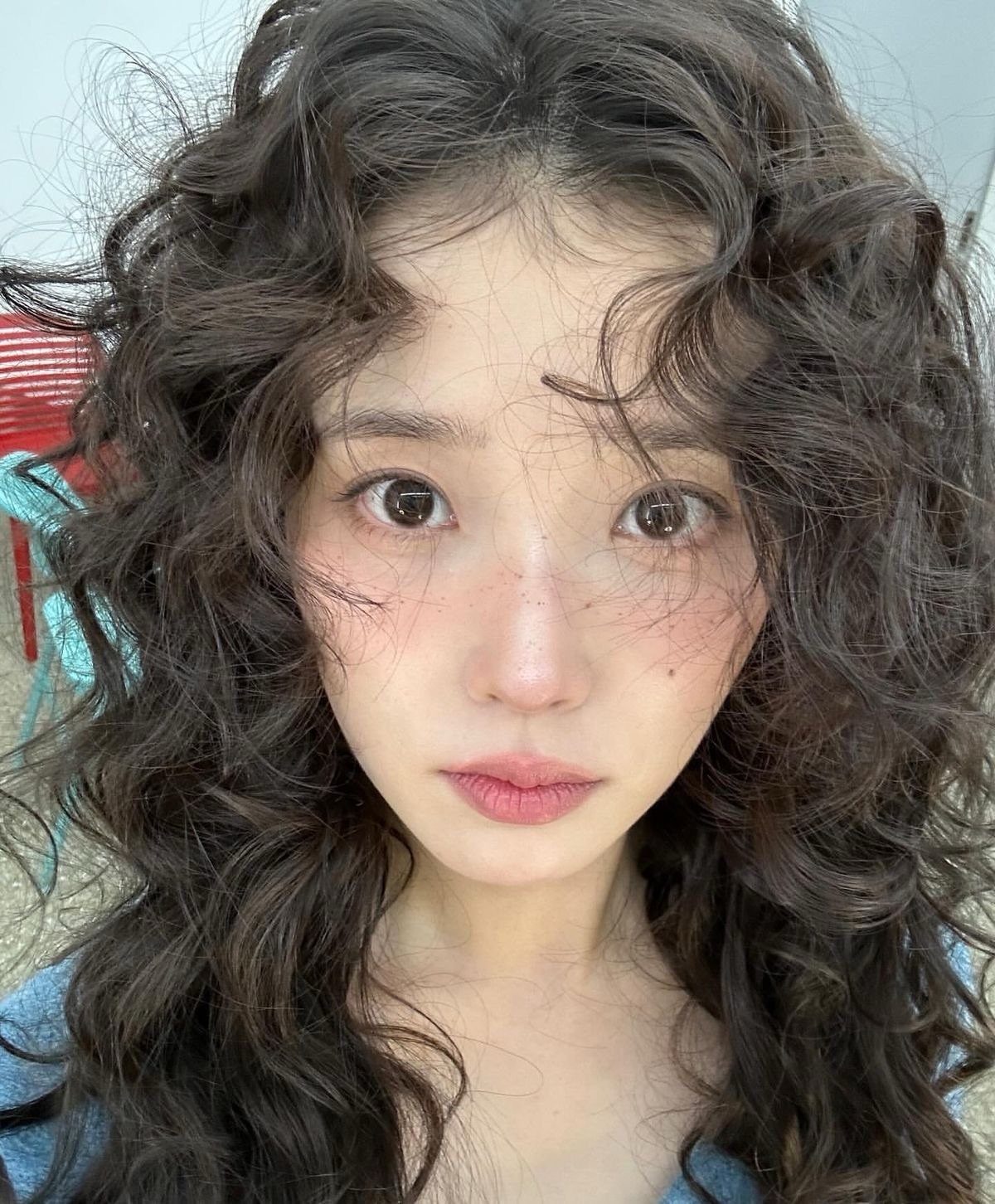 Woman with long dark curls arranged in loose face-framing bangs