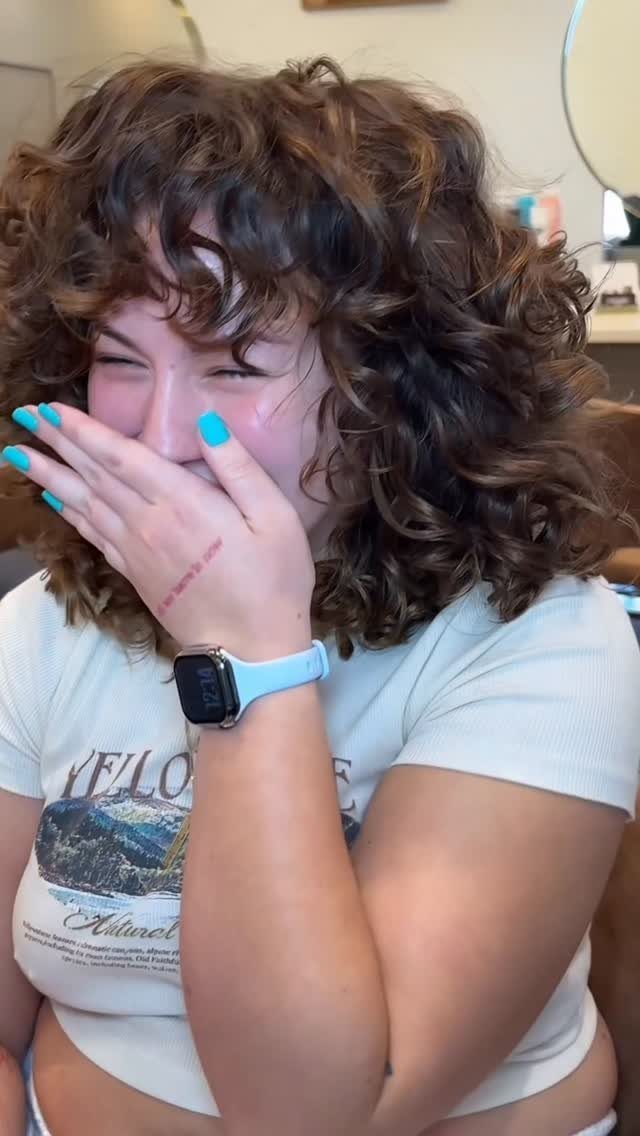 Person with layered curly bangs blending into voluminous dark brown curls