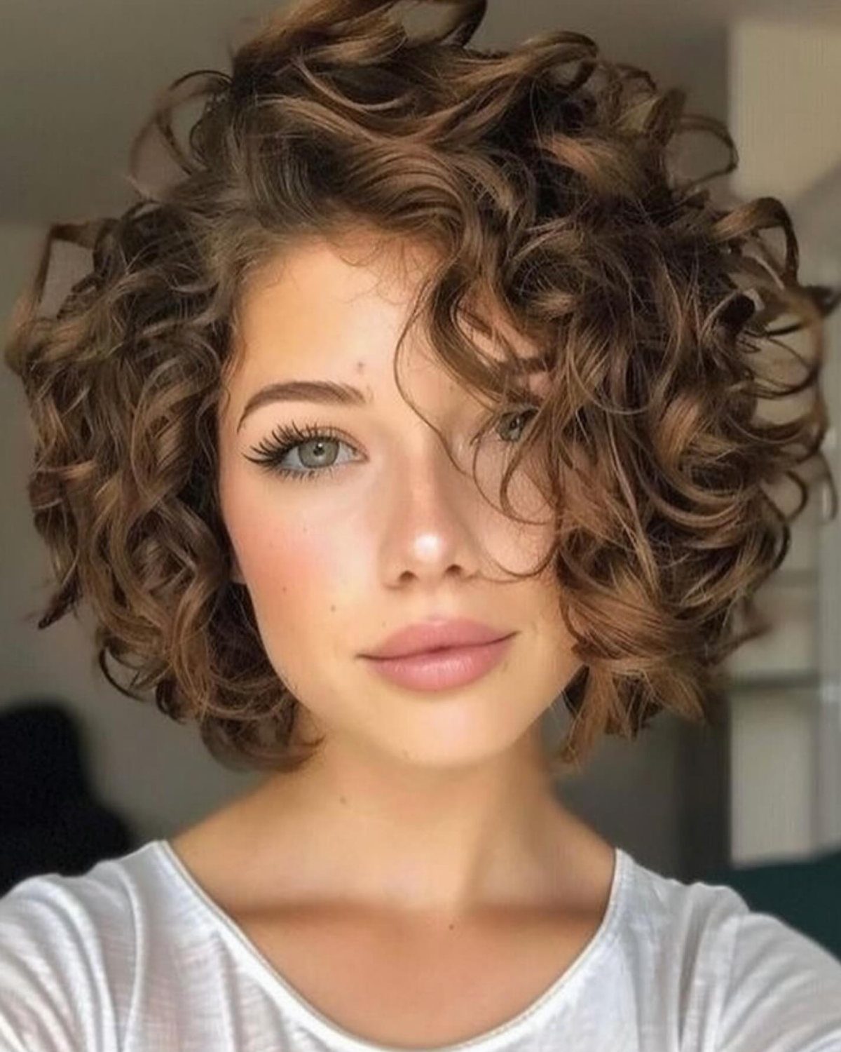 Woman with a rounded chin-length curly bob and loose forehead-framing curls