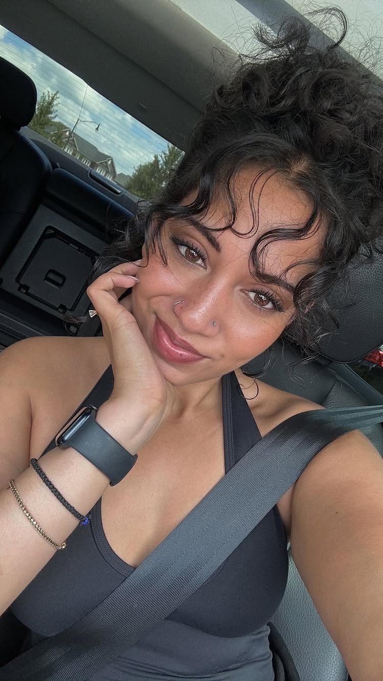 Woman showing wispy curly bangs while posing in a car
