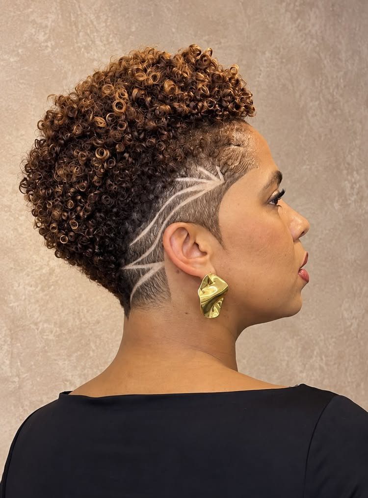 Person showing a curly pixie cut with shaved artistic side design